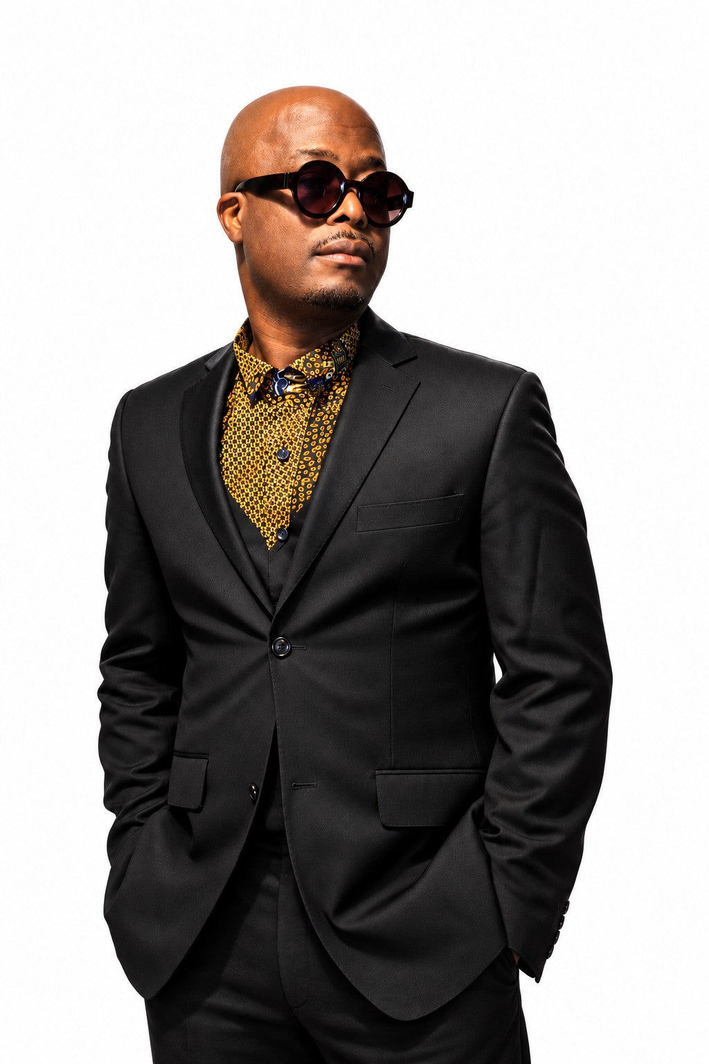 Akin black chino and gold Ankara shirt styled beneath a black blazer on a model against a white background.