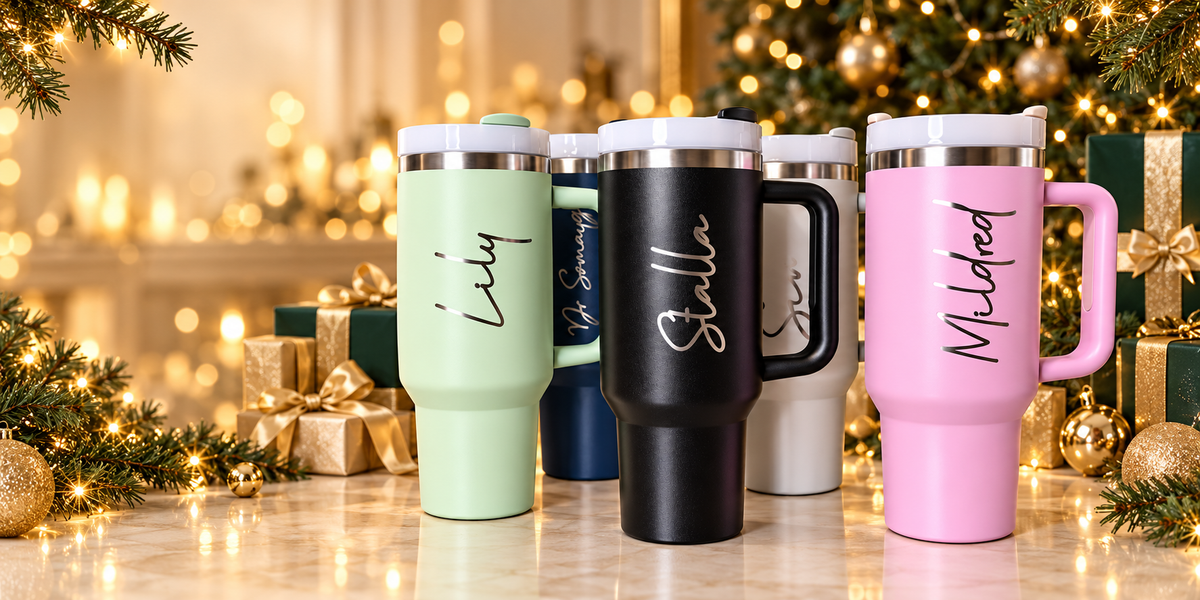 Personalised tumblers surrounded by Christmas gifts, evergreen decorations and warm golden lights